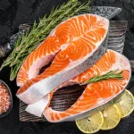 fresh salmon bali – raw salmon steaks on butcher board with rosemary and lemon