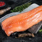 fresh salmon fillet bali – raw salmon fillet with herbs on dark background