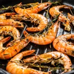 grilled tiger prawn bali – grilled prawns in black skillet with herbs