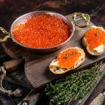 ikura bali – red caviar sandwiches on wooden board, top view