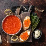 red caviar bali – ikura sandwiches with butter and thyme on wooden board