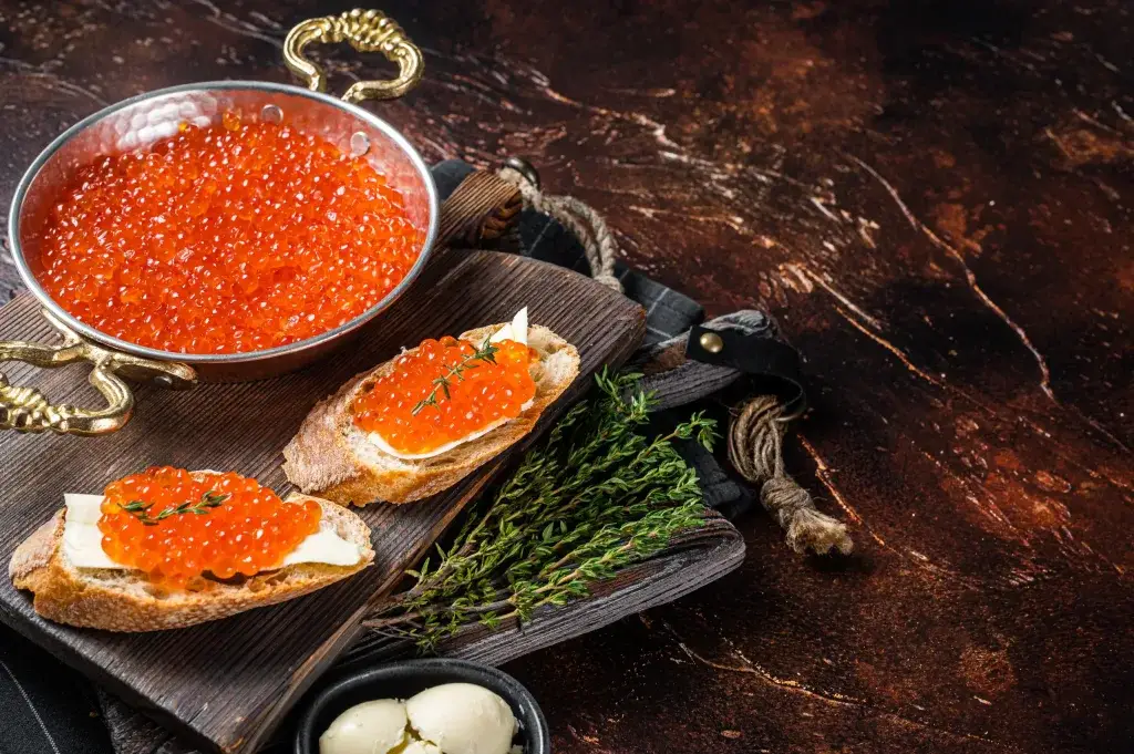 red caviar bali – salmon roe ikura on bread slices with fresh herbs