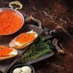 red caviar bali – salmon roe ikura on bread slices with fresh herbs