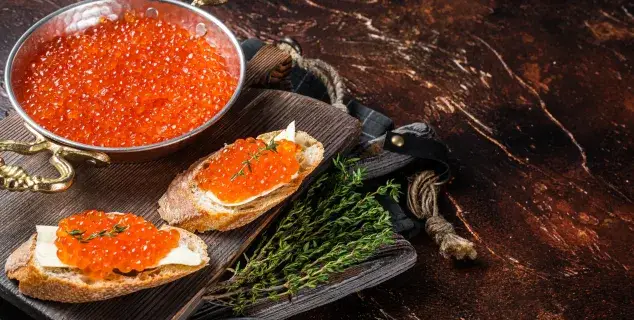 red caviar bali – salmon roe ikura on bread slices with fresh herbs