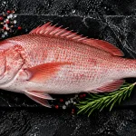 red snapper bali – whole fresh red snapper on slate board with salt and rosemary