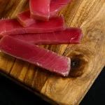 Smoked tuna Bali — thin slices of cold-smoked tuna on a wooden cutting board