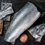 whole salmon bali – raw cut salmon on wooden board with cleaver
