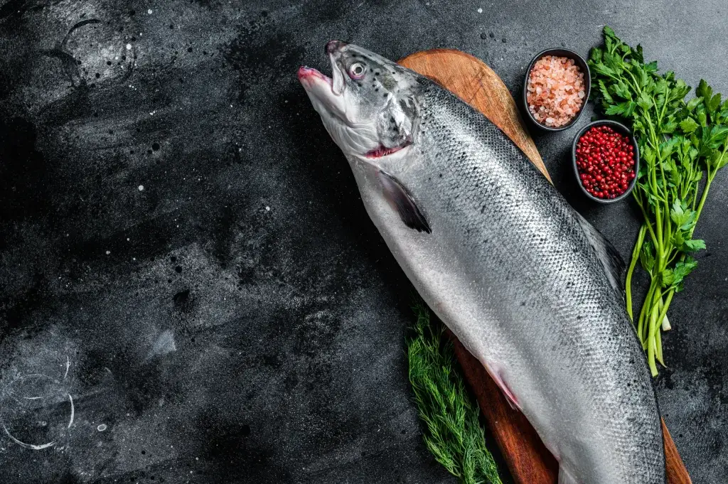 whole salmon bali – raw whole salmon on wooden board with herbs