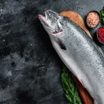 whole salmon bali – raw whole salmon on wooden board with herbs