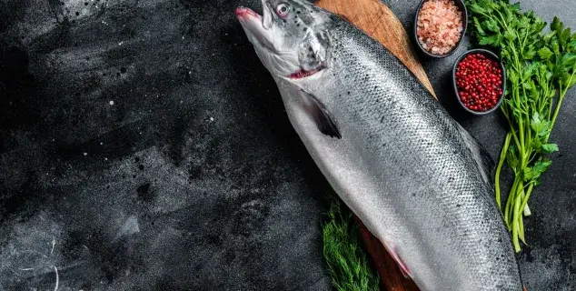 whole salmon bali – raw whole salmon on wooden board with herbs